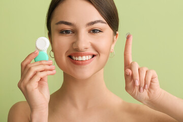 Young woman with contact lenses on color background