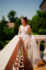 Fototapeta premium a beautiful bride in a transparent lace robe stands on the terrace. 