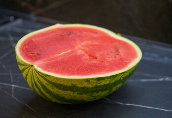 half of the watermelon lies on the kitchen table