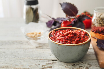 Bowl of tasty pesto sauce on wooden table