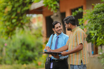 young india bank officer completing paper work with farmer.