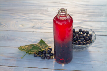 Compote or mors made from black currant berries in a bottle on the table in the garden © Olga