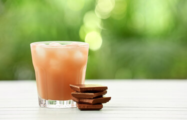 Glass of tasty chocolate milk on table outdoors, closeup