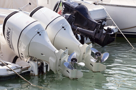 Pair of white marine engines outboard model Suzuki 200 mounted on a white fiberglass pleasure boat moored at harbor
