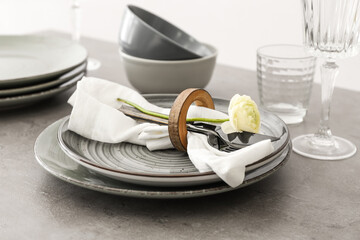 Stylish table setting and ranunculus flower on grey background