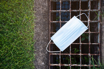 Close up of used mask thrown on the ground.Discarding face mask on floor in public places.grass in the garden