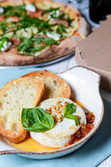 Pizza with mozzarella, salmon slices, fresh arugula. Served with baked cheese camembert, pizza delivery box.