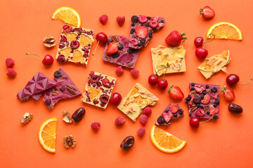 Handmade chocolate bars with fruits and berries on color background