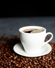Warm cup of coffee with coffee beans over black background. Coffee time, close up, selective focus.