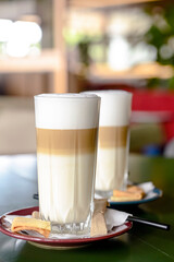 Glass of hot Latte macchiato coffee close up. Two glasses of coffee latte. Blurred background.