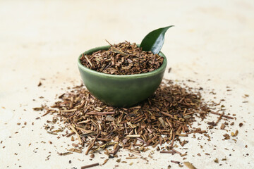 Bowl of dry hojicha green tea on light background