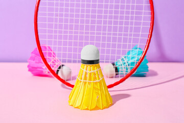Badminton racket and shuttlecocks on color background