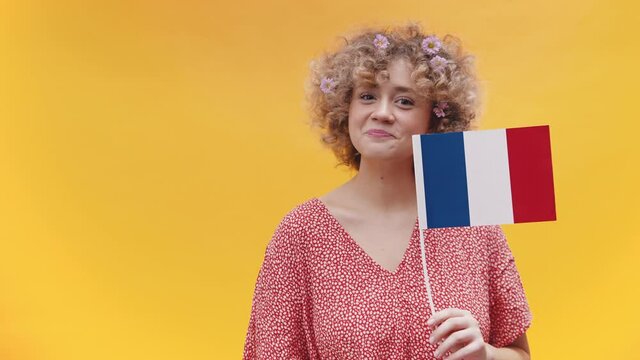 Young woman with curly hair pointing finger towards the french flag