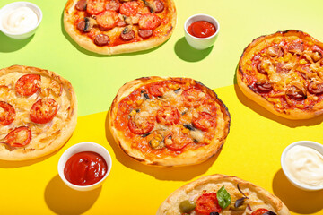 Fototapeta na wymiar Tasty mini pizzas and sauces on color background