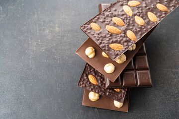 Chocolate bars with walnuts a tower on a black background. Milk and Dark Chocolate With Almonds and Hazelnuts Isolated