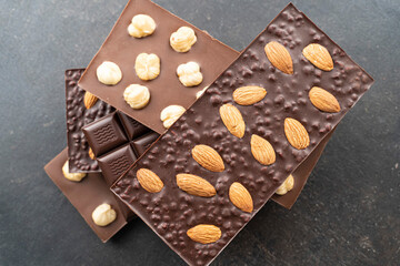 Chocolate bars with walnuts a tower on a black background. Milk and Dark Chocolate With Almonds and Hazelnuts Isolated