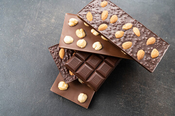 Chocolate bars with walnuts a tower on a black background. Milk and Dark Chocolate With Almonds and Hazelnuts Isolated