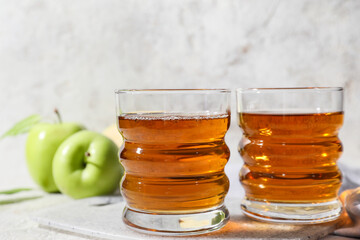 Glasses of apple juice on light background