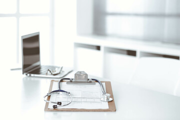 Stethoscope and clipboard with medication history records are on the table at the doctor's working place. Medicine and health care concept