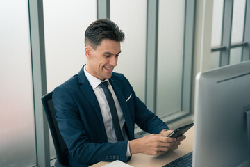 Adult smart business man in suit outfit sitting and working on tablet with happy and smile in modern office