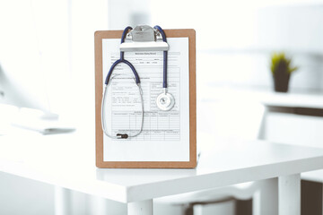 Stethoscope and clipboard with medication history records are on the table at the doctor's working place. Medicine and health care concept