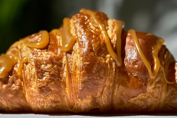 Croissant with caramel and nuts. Hard light. White background. Texture, close up, selective focus