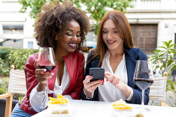 two adult women after work in a city, person having fun looking at smartphone for social media,...