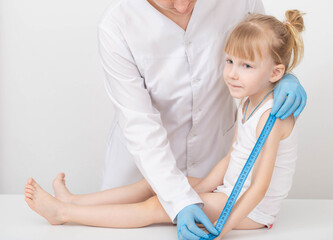 The doctor measures the length of the arm of a child of a girl 4 years old. Child growth measurement and anthropometric data concept. Copy space for text
