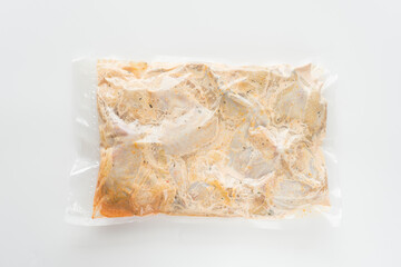 Meat marinated in sauce in a vacuum bag on a white plate