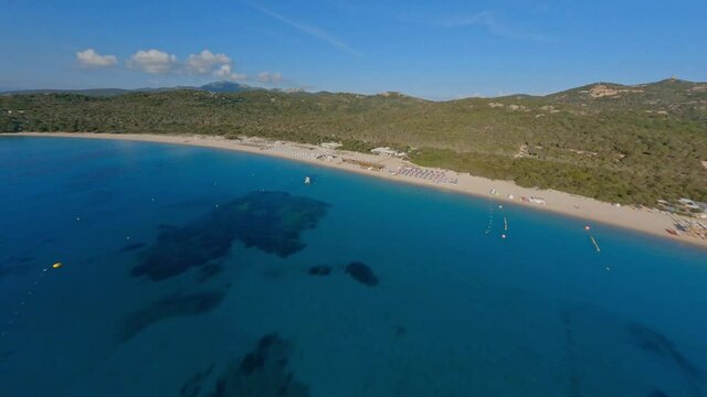 FPV video, view from above, aerial view from an FPV drone flying at high speed over a coastline with a white sand beach bathed by a turquoise, crystal clear water. Sardinia, Italy.