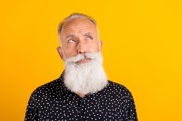 Photo of minded serious old man look empty space thoughtful idea plan isolated on yellow color background