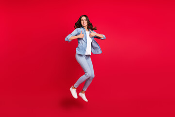 Full length photo of young girl happy positive smile jump up show thumbs-up feedback isolated over red color background