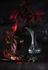 still life with red wine in a jug and pomegranate