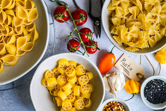 Raw pasta on a table with ingredients for making a sauce