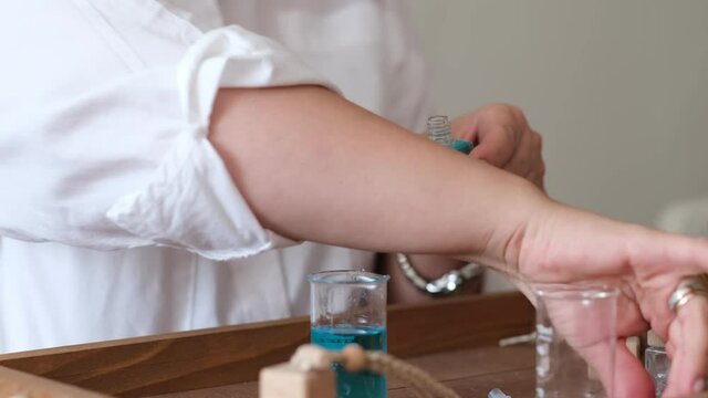 Close-up of a pipette with oil and a glass bottle. woman pouring perfume in bottle. Perfume creating workshop