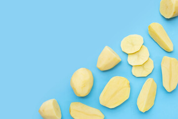 Raw peeled potatoes on blue background