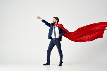 man in suit with red cloak hold hand above head superhero light background © SHOTPRIME STUDIO