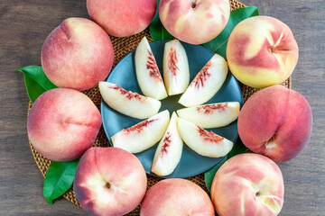 White peach on black plate on wooden table, Top view Fresh peach with slices closeup.