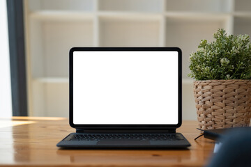 Shot of digital tablet with blank white screen, keyboard, cup of coffee on workspace desk