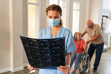 Ärztin mit Mundschutz betrachtet eine MRT Aufnahme