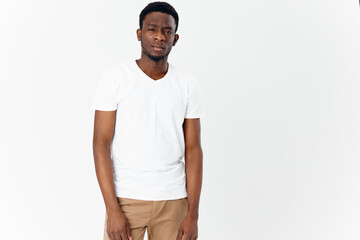 Fototapeta premium a young man of African appearance in beige trousers and a white T-shirt looks forward 