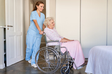 Frau vom Pflegedienst schiebt eine Seniorin im Rollstuhl