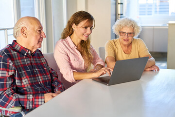 Tochter hilft Senioren Paar beim Videochat am Laptop