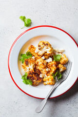 Spicy baked cauliflower with feta cheese in white plate. Vegetarian food concept.
