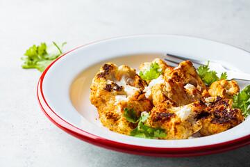 Spicy baked cauliflower with feta cheese in white plate. Vegetarian food concept.