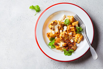 Spicy baked cauliflower with feta cheese in white plate. Vegetarian food concept.