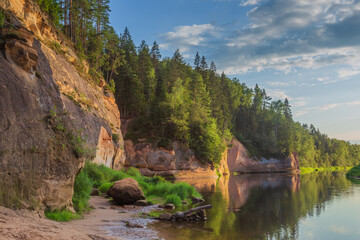 Fototapeta na wymiar Peaceful landscape with Gauja river and red sandstone Erglu kliffs steep rocks in Gauja National Park in Valmiera area