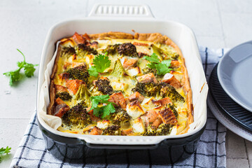 Quiche pie with salmon and broccoli in baking dish.