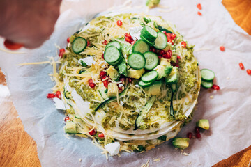 Messy food table with colorful vegetarian healthy dish - tortilla pie with pomegranate and avocado, cucumber and cheese