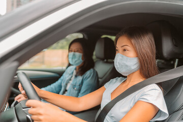 Car driving Asian woman wearing face mask inside during coronavirus pandemic. Driver with passenger on road trip drive.